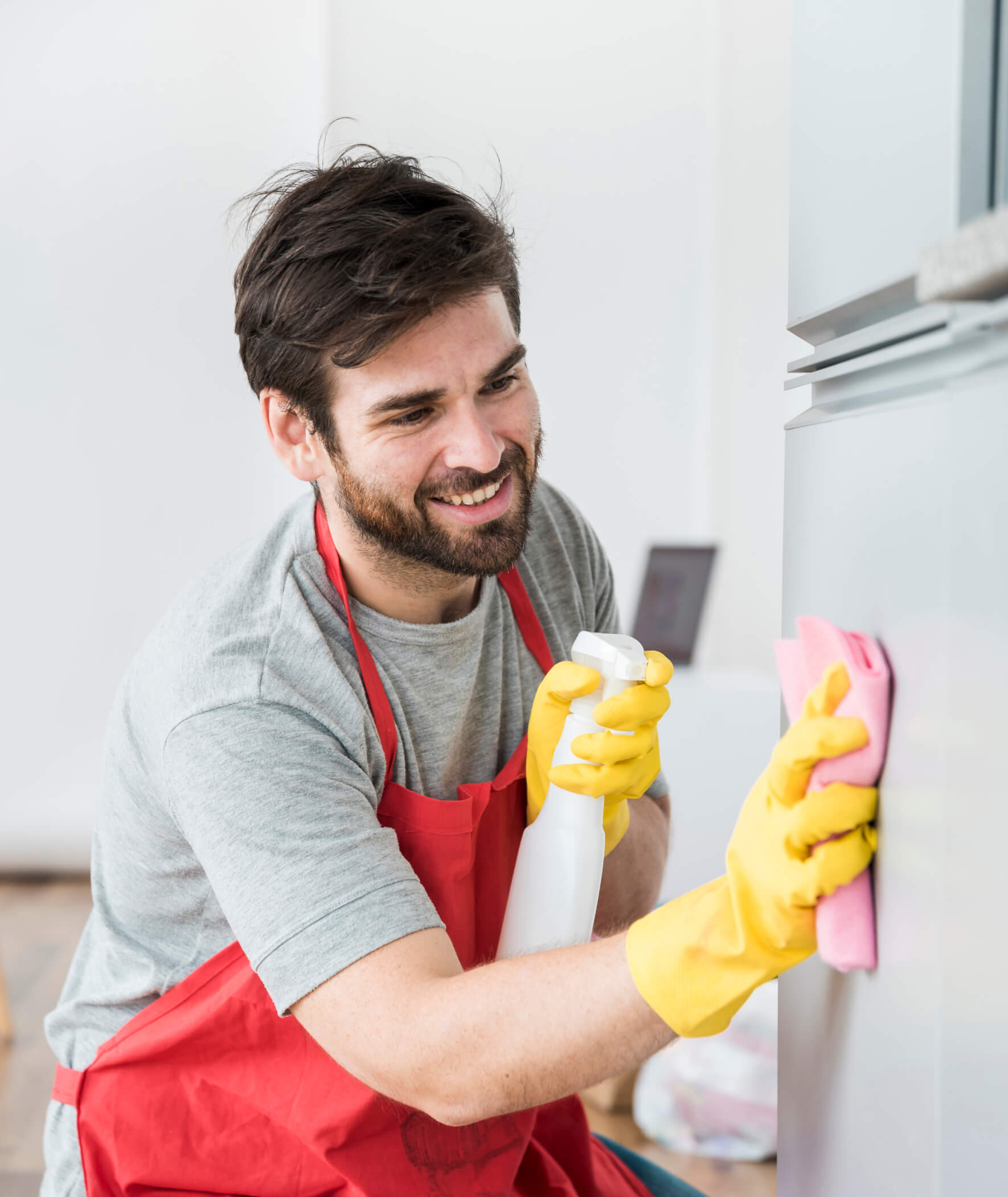A man in an apron cleaning a refrigerator.