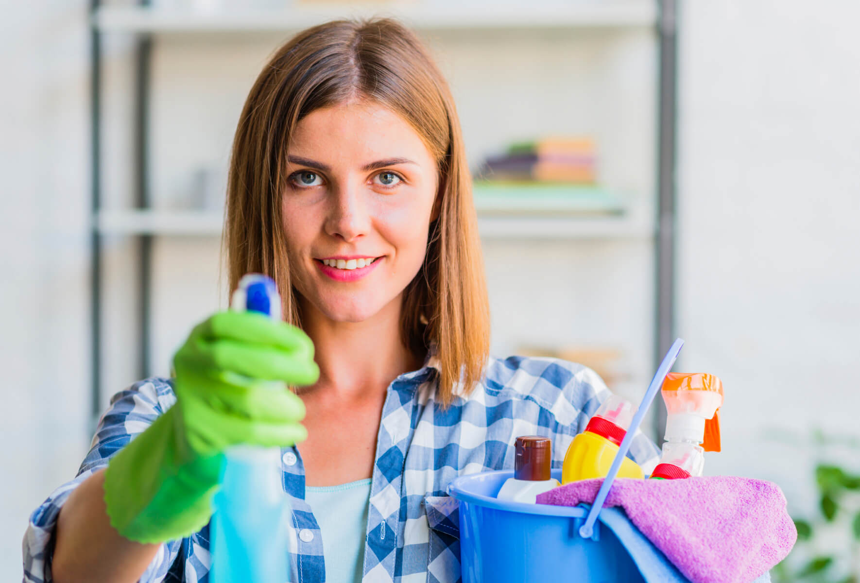 A woman holding a bucket of cleaning supplies.